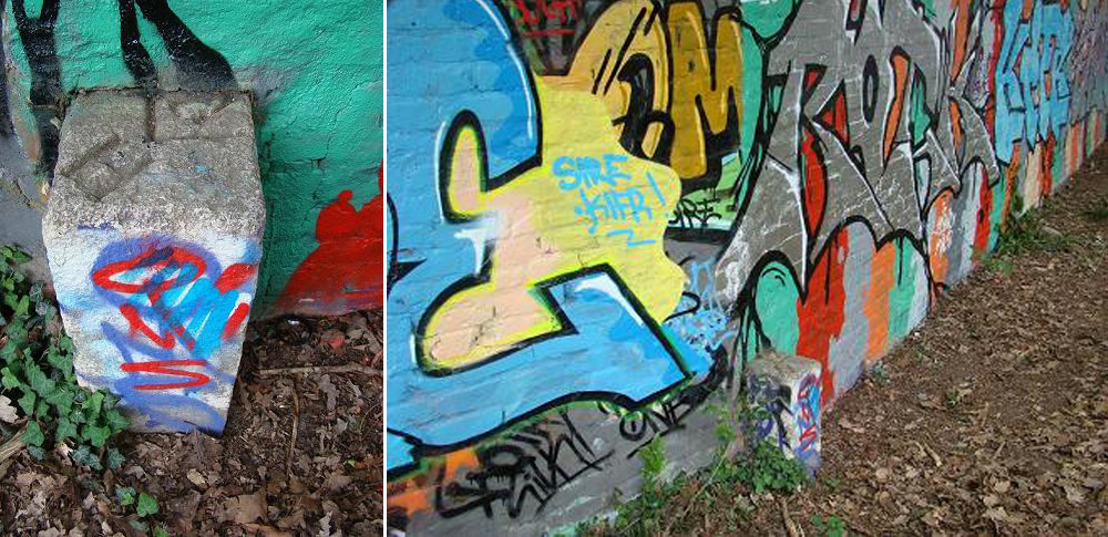 Der Grenzstein steht vom Eingang des Spielplatzes aus gesehen an der linken Grundstücksmauer. Da der Grenzstein mit den gleichen Graffitifarben besprüht ist wie die dahinter stehende Mauer, ist er nicht gleich zu sehen.